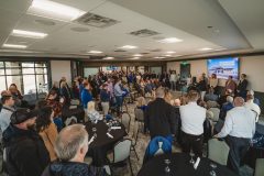 Speaker before crowd in bright room