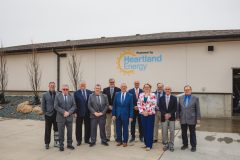 Group of people standing in front of building with Heartland Energy log