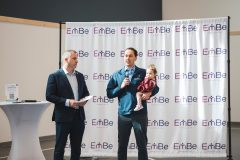 Man holding a child and speaking into microphone