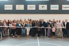 Crowd stands with ceremonial ribbon