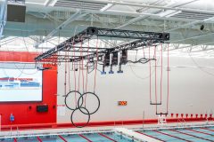 Closeup of obstacle course rings and ropes hanging over an interior pool.