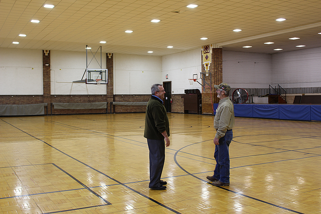 Heartland Customer Relations & Marketing Manager Steve Moses, left, visits with Madison Electric Superintendent Dennis Poppen under the new lights in the Madison Armory.