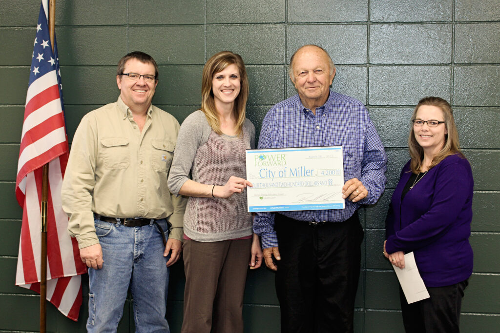 Heartland Communications Manager Ann Hyland, second from left, presents an energy efficiency grant to Miller Electric Superintendent Bill Lewellen, Mayor Ron Blachford and Finance Officer Sheila Coss.