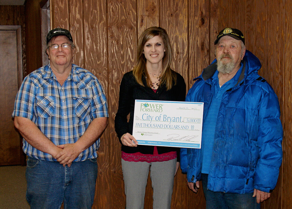 Heartland Communications Manager Ann Hyland, center, presents an energy efficiency grant to Bryant Electric Superintendent Garry Ladwig and Mayor Albert Yalowizer.