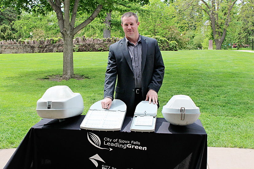 Sioux Falls Light Superintendent Jerry Jongeling stands with new LED streetlighting fixtures (center) which will replace traditional HPS lights (left and right) in the city's pilot project.