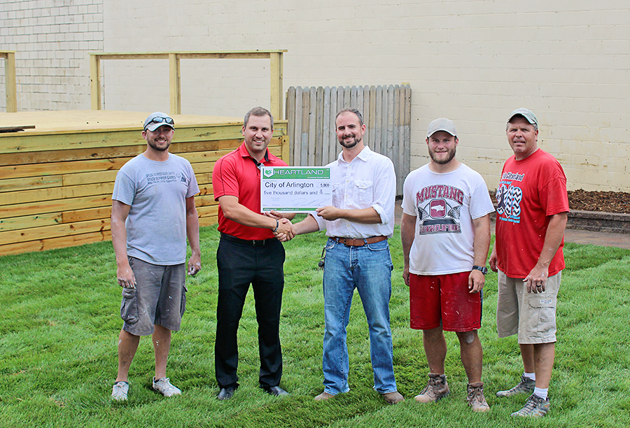 Heartland Director of Economic Development Casey Crabtree, second from left, presents a grant to Arlington Community Development Corporation Executive Director Jason Uphoff near the stage in the new Main Street Square in Arlington. Also pictured, left to right, Nathan Gruis, Dan Lesnar and Steffensen Construction owner John Steffensen, who constructed the stage for free.