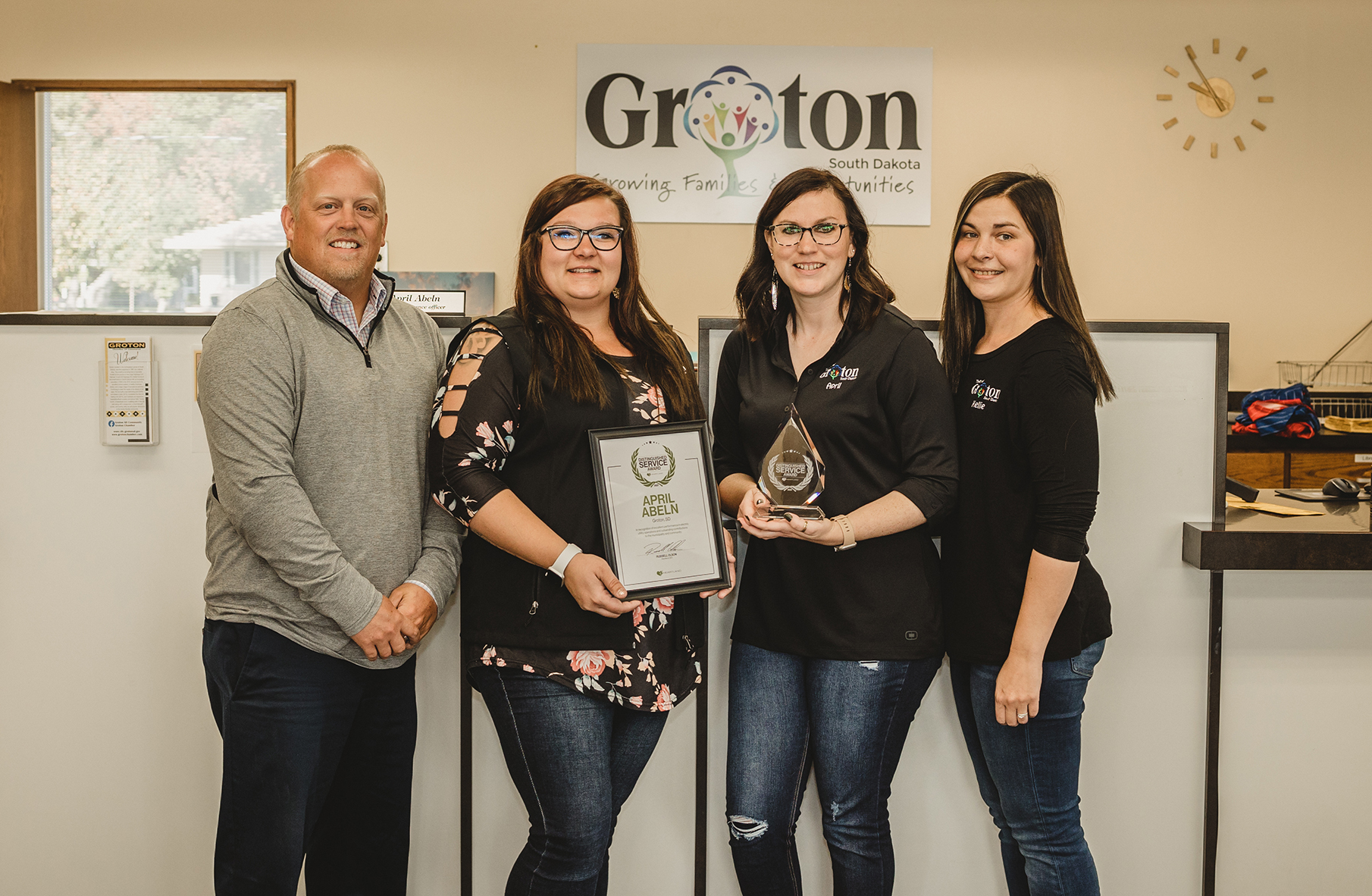 April Abeln holding an award and standing with co-workers