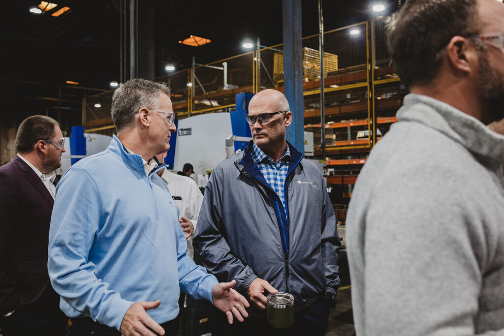 GOED Commissioner Steve Westra, left, visits with Heartland CEO Russell Olson while touring Gehl.
