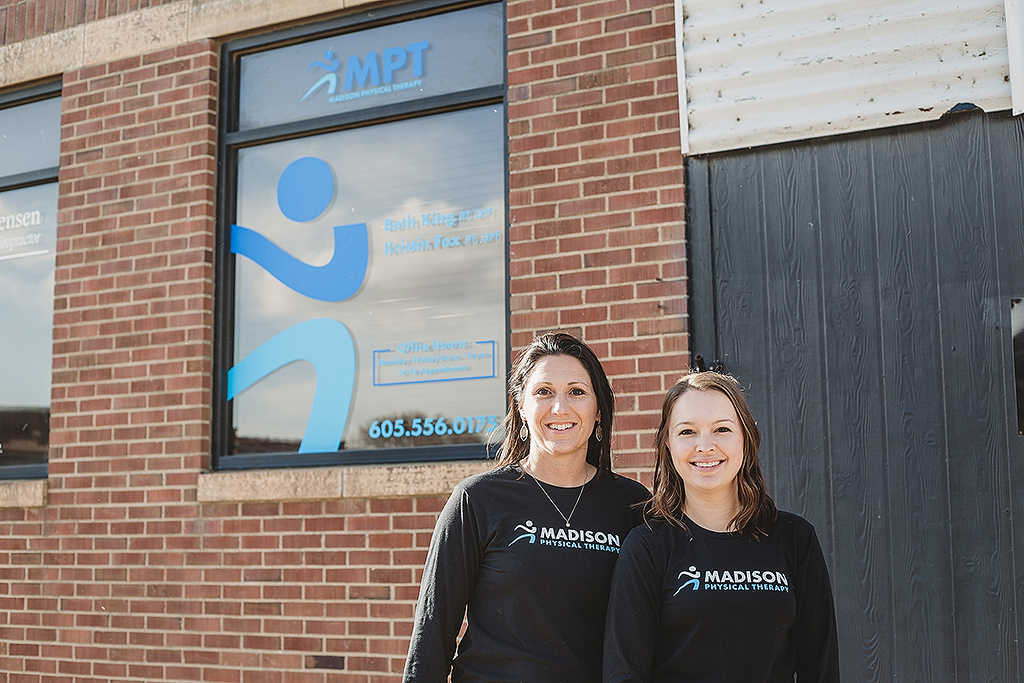 two employees standing in front of madison physical therapy building