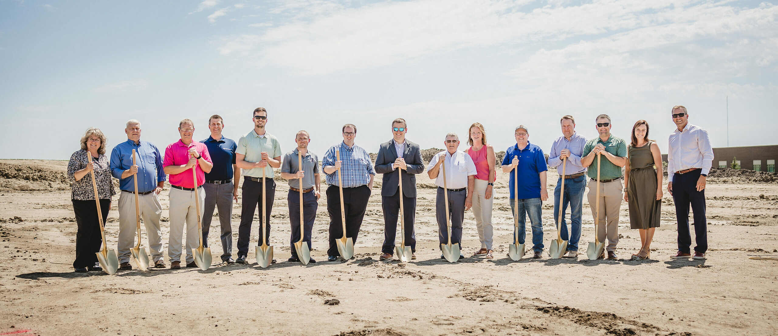 Group of people stand side by side with gold shovels